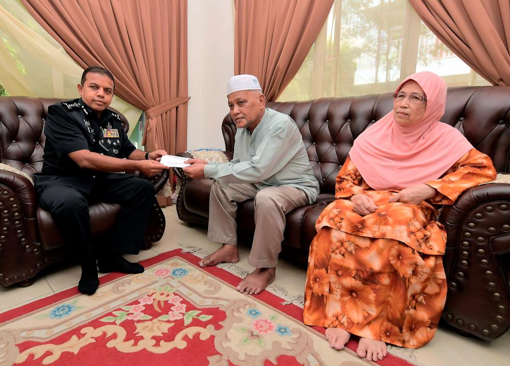 Johor police chief Datuk Ayob Khan Mydin Pitchay (L) presents Aidilfitri aid to Mt Najik Nawi, imam of the Masjid Tunku Laksamana Abdul Jalil, who is stricken by gout. — Bernama