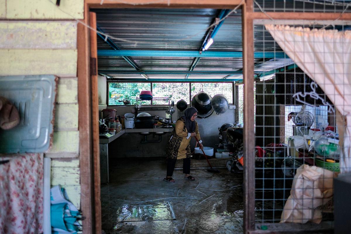 Seorang penduduk Norhayati Ariffin melakukan kerja-kerja pembersihan selepas kediamannya dilanda banjir semalam ketika tinjauan fotoBernama di Kampung Melayu Raya, Pekan Nenas hari ini-fotoBERNAMA