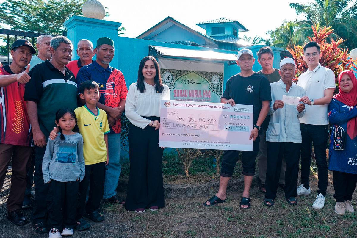 Timbalan Menteri Komunikasi Teo Nie Ching menyampaikan replika cek bernilai RM15,000 kepada Pengerusi Surau Nurul Haq Kampung Sungai Sayong 1 Mohd Anuar Repan (lima, kanan), hari ini, susulan insiden van jenazah milik surau itu yang dicuri dan remuk teruk akibat kemalangan Khamis lepas-fotoBERNAMA
