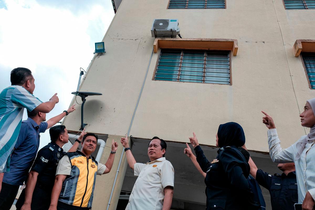 Deputy Minister of Works Datuk Seri Ahmad Maslan (centre) points to cracks caused by a recent minor earthquake in Segamat during a visit to the Segamat District Police Quarters site today. – BERNAMA