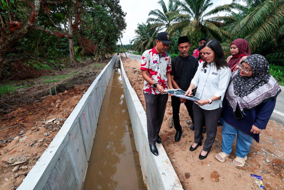 Timbalan Menteri Komunikasi merangkap Ahli Parlimen Kulai, Teo Nie Ching (dua dari kanan) meneliti pelan projek bersama Ketua Kampung Melayu Bukit Batu, Salehan Mansor (dua dari kiri) dan Penghulu Mukim Bukit Batu, Mohamad Norzaharuddin Kasimon (kiri) semasa Lawatan Tapak Projek Banjir di Jalan Masjid, Kampung Melayu Bukit Batu, hari ini.- fotoBERNAMA