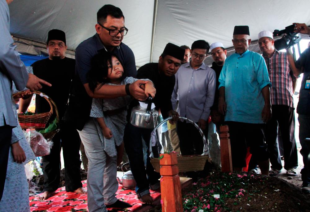 Eva Arianna, 4, poured roses and water onto the body of her father, Datuk Dr Md Farid Md Rafik, after the body was buried at the Sheikh Haji Ahmad Waqf Muslim Cemetery in Kampung Chokoh, Serkat, at 5.30pm on Sept 22, 2019. - Bernama