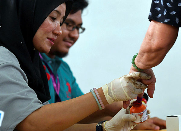 Election Commission personnel dips a voter’s finger in indellible ink during the voting process at Tanjung Piai’s by-election today — Bernama