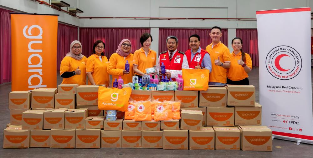 Guardian Malaysia senior manager of public relations and events Jennifer Wong (4th from left) handing over flood aid items to MRC secretary-general Hakim Hamzah (4th from right).