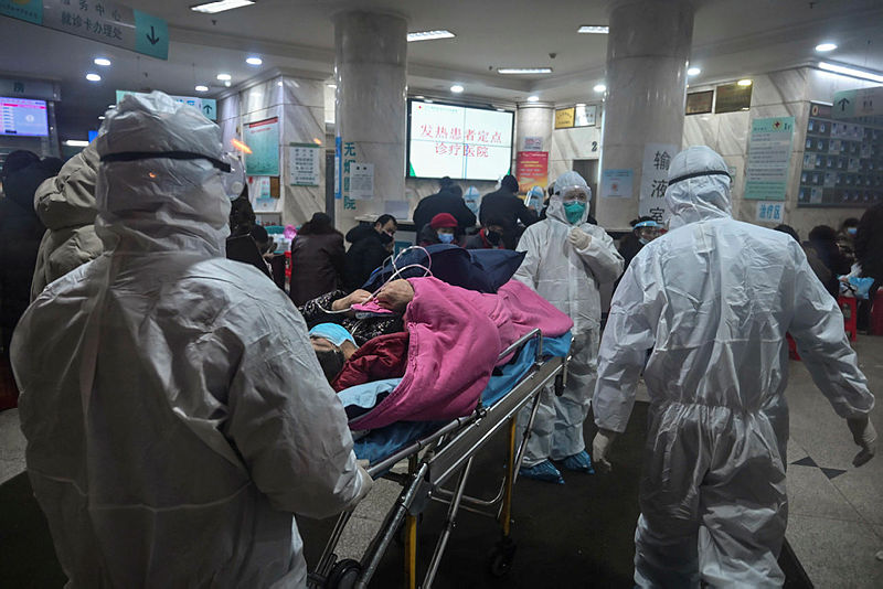 In this photo taken on Jan 25, 2020, medical staff wearing protective clothing to protect against a previously unknown coronavirus arrive with a patient at the Wuhan Red Cross Hospital in Wuhan. The number of confirmed deaths from a viral outbreak in China has risen to 54, with authorities in hard-hit Hubei province on January 26 reporting 13 more fatalities and 323 new cases. — AFP