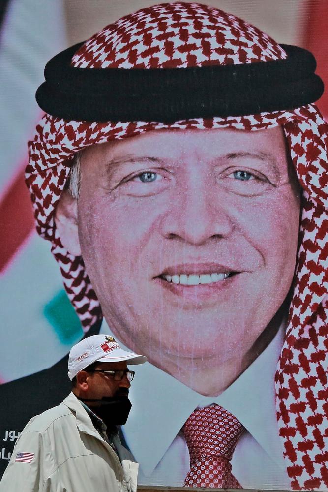 A man walks past a poster of Jordan's King Abdullah II on a street in the capital Amman. –AFP