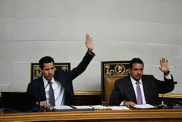 The president of Venezuela’s opposition-led National Assembly, Juan Guaido (L), raises his arm next to second vice president Stalin Gonzalez during a session at the Federal Legislative Palace in Caracas. — AFP