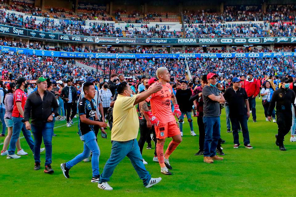 Soccer players and people walk on the field at the Corregidora stadium after clashes leave least 22 people injured in a brawl when soccer fans stormed the field during a top flight match between mid-table Queretaro and last year’s Liga MX champions Atlas, in Queretaro, Mexico March 5, 2022. REUTERSPIX