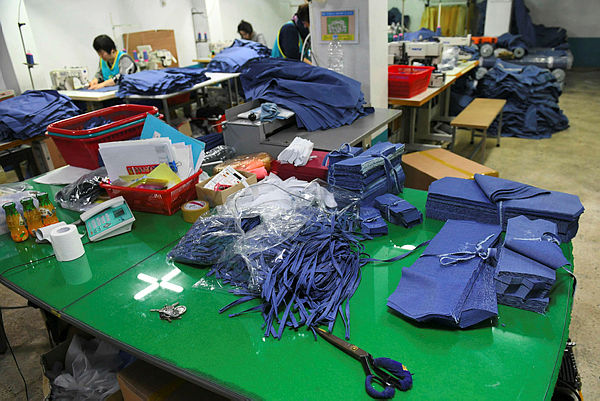 Picture shows workers making uniforms in the basement of a textile company in Seoul. — AFP