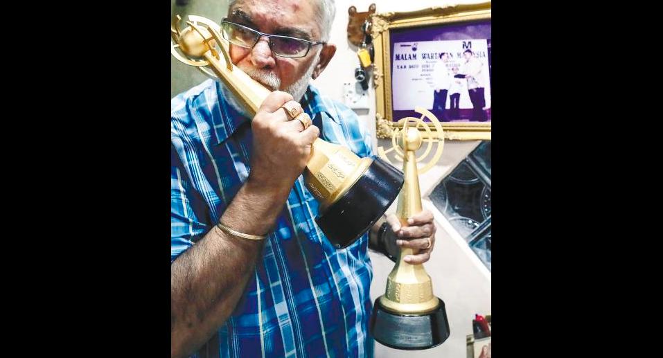 WHAT A RIDE ... Former TV personality Datuk Karam Singh Walia kisses one of his two ‘Anugerah Seri Angkasa’ award. — Sunpix by Ashraf Shamsul