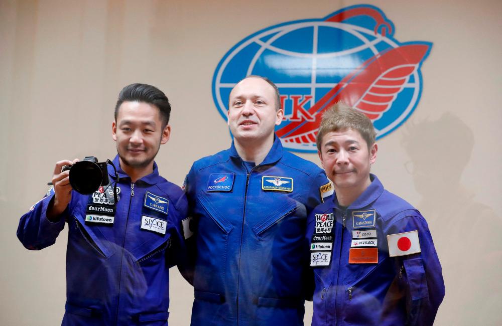 Russian cosmonaut Alexander Misurkin (C), Japanese billionaire Yusaku Maezawa (R) and his assistant Yozo Hirano pose for pictures behind a glass wall following a meeting of the State Commission in Baikonur on December 7, 2021. Space tourists Yusaku Maezawa and his assistant Yozo Hirano, led by Roscosmos cosmonaut Alexander Misurkin, will take part in a mission on the Soyuz MS-20 spacecraft to the International Space Station (ISS) scheduled for December 8, 2021. AFPpix