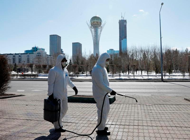 Workers wearing protective suits spray disinfectant on the street to prevent the spread of coronavirus disease (Covid-19), in central Nur-Sultan, Kazakhstan March 24, 2020. — Reuters