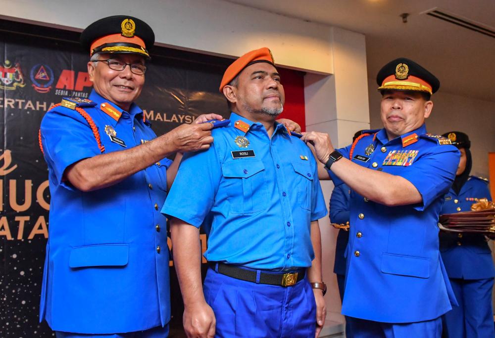 Minister in the Prime Minister’s Department (Special Functions) Datuk Seri Mohd Redzuan Yusof (L) with Chief Commissioner of the Civil Defence Force Datuk Roslan (R), give the rank of honourary officer to Prof Teknologi Dr Mohd Rosli Hainin at an award ceremony in Kota Bharu today. - Bernama