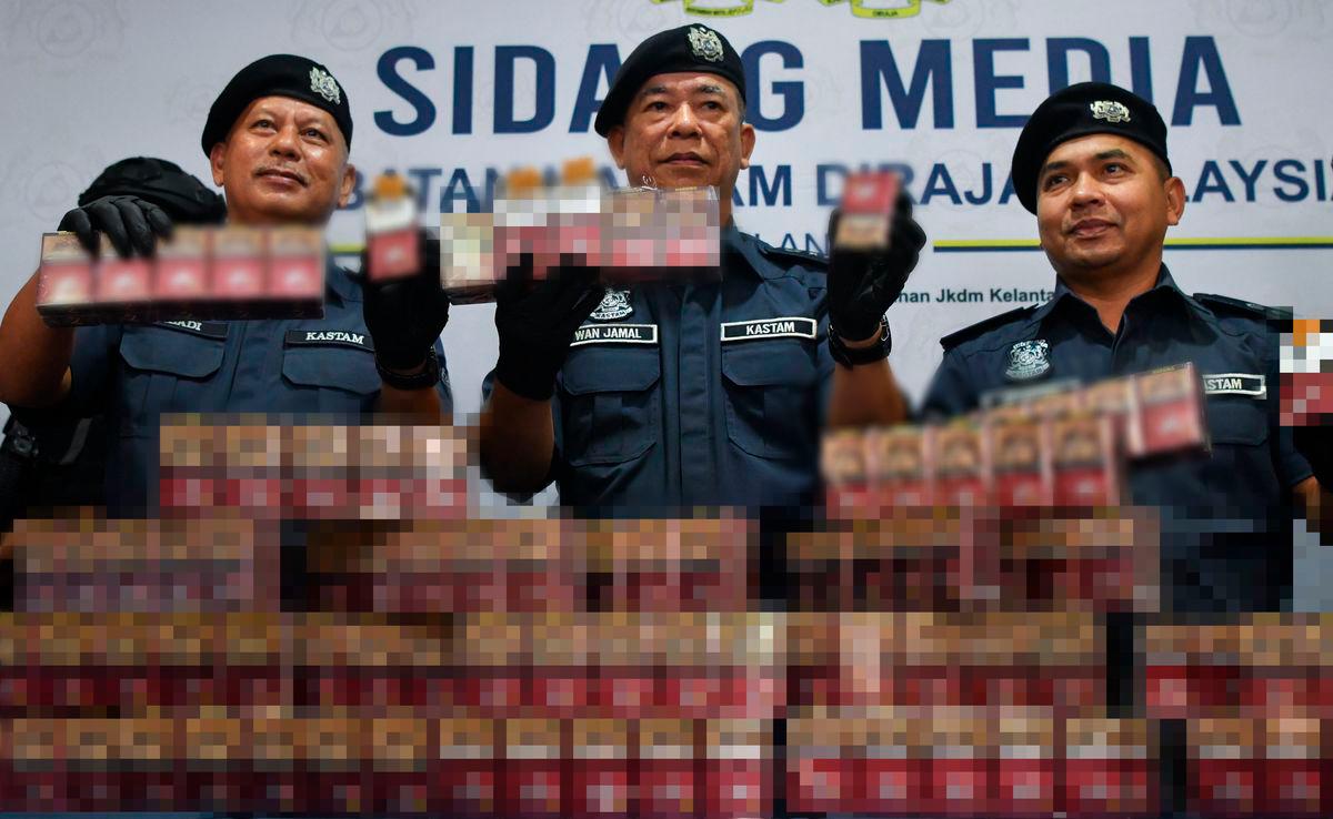 Pengarah Jabatan Kastam Diraja Malaysia (JKDM) Kelantan Wan Jamal Abdul Salam Wan Long (tengah) bersama para pegawai menunjukkan sebahagian rokok putih yang dirampas pada sidang media di Wisma Kastam Padang Bongor hari ini - foto BERNAMA