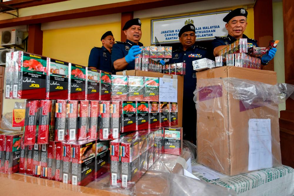 PASIR MAS, March 27 -- Director of the Royal Malaysian Customs Department (JKDM) Kelantan Wan Jamal Abdul Salam Wan Long (right) with his officers showing some of the smuggled cigarettes worth RM551,749 that were successfully seized in two raids on premises in Kuala Krai, last Monday. BERNAMAPIX