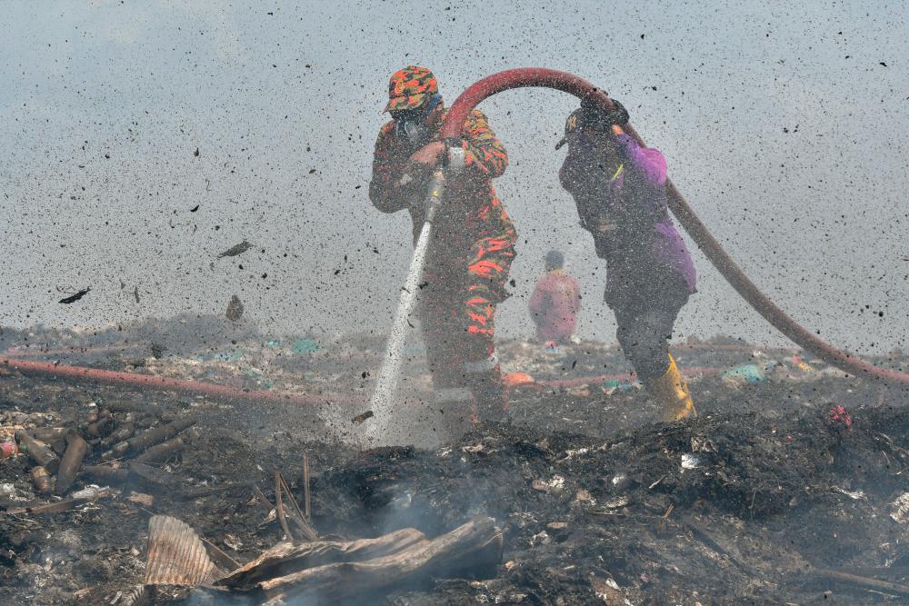 BACHOK, May 3 -- Firefighters and rescue workers assisted by garbage disposal contract workers do extinguishing work in the Beris Lalang landfill fire area today. BERNAMAPIX