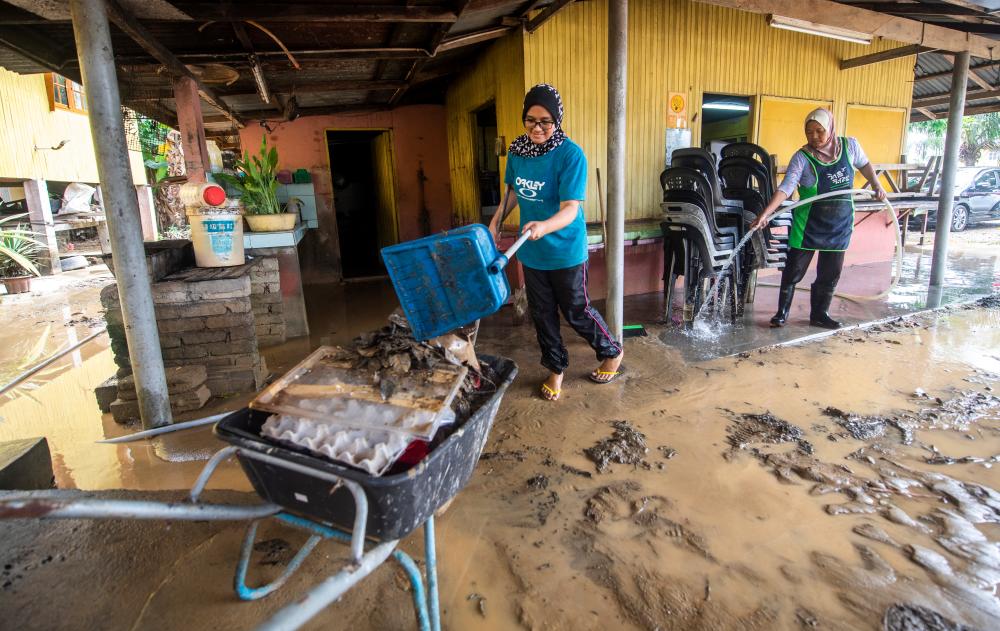 Eatery owner Sawiyah Jusof, 57, (left) and daughter Munirah Mohd Zulkafli, 25, cl;enaing up their premises after the flood-- fotoBERNAMA (2021) Copyright Reserved.