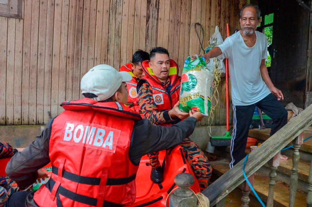 PASIR MAS, 17 Dis -- Anggota Bomba dan Penyelamat Rantau Panjang membantu Badan Bukan Kerajaan Yayasan Raja Shamri (YRS) menyampaikan bantuan barangan keperluan asas kepada salah seorang penduduk Kampung Padan Licin yang terjejas akibat bencana banjir sejak seminggu lalu. fotoBERNAMA