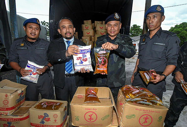 Filepix taken on June 25 shows KPDNHEP director Adnan Abd Rahman (two, left) along with his officers showing smuggled wheat flour and cooking oil that were seized in Rantau Panjang. — Bernama