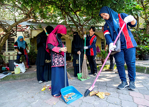 Kelantan Immigration Department Deputy Director, Siti Khadijah Hamzah (R) taking part in the departments CSR project to clean Salimah Orphanage near Telong today. — Bernama