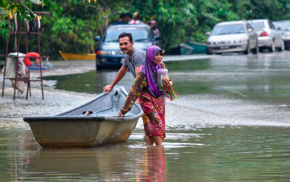 Penduduk menggunakan perkhidmatan sampan untuk melakukan kegiatan harian berikutan kawasan kampung masih ditengelami banjir ketika tinjauan di Kampung Tersang, Rantau Panjang hari ini. fotoBERNAMA