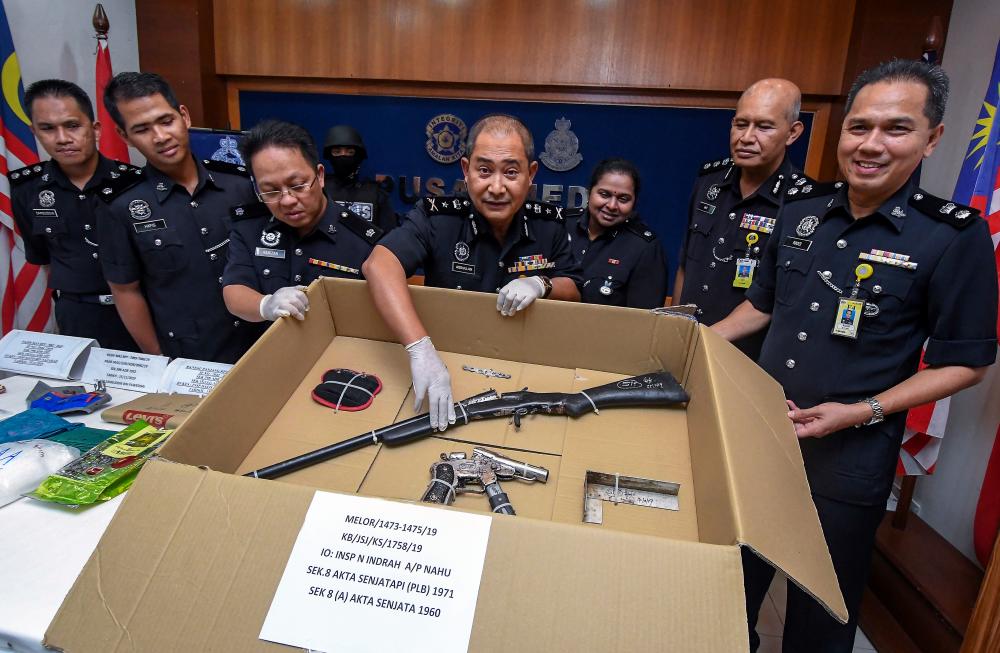 Kelantan Deputy Police Chief SAC Abdullah Mohammad Piah (c) displays a shotgun and a homemade pistol, seized during a raid in Kampung Padang Mokkan, at a press conference at the Kelantan police headquarters today. - Bernama