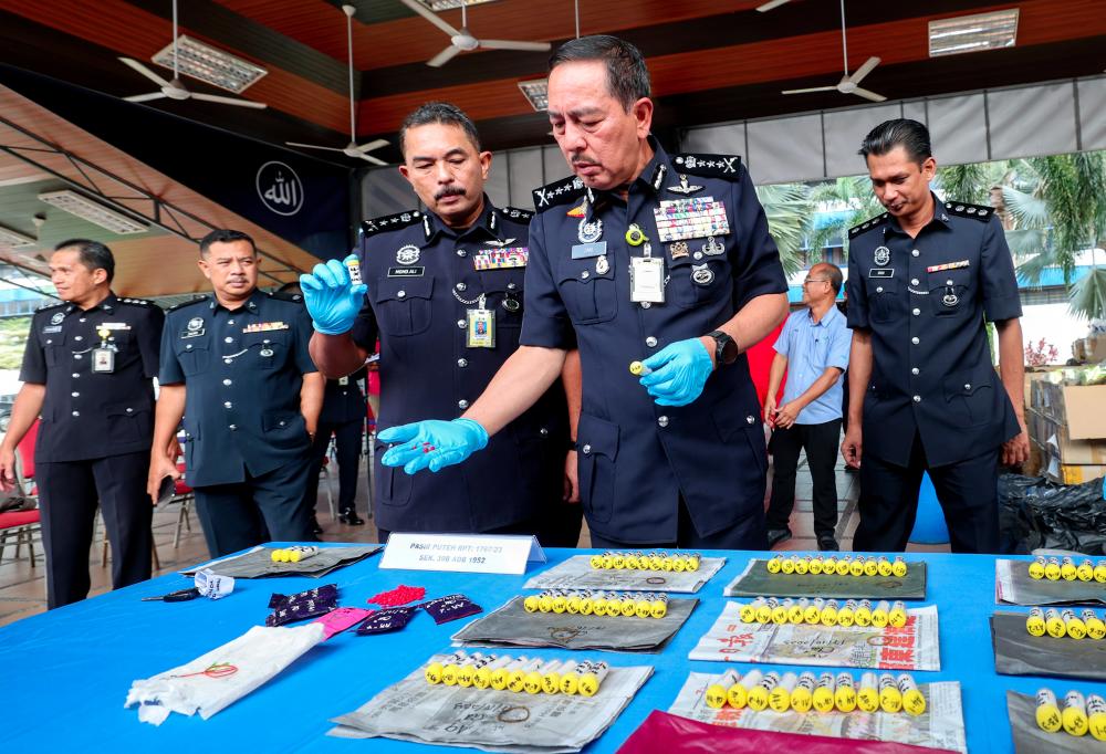 Ketua Polis Kelantan Datuk Muhamad Zaki Harun (kanan) menunjukkan sebahagian dadah yang berjaya dirampas daripada seorang wanita bersama 94 botol dadah jenis heroin dan 1,000 biji Pil Yaba bernilai RM199,000 di sebuah rumah di Kampung Lembah Cherang Ruku, Pasir Puteh pukul 9.25 pagi semalam sempena majlis pelupusan barang kes dadah di Ibu Pejabat Polis Kontinjen (IPK) Kelantan pada Okt 18 2023. - fotoBERNAMA