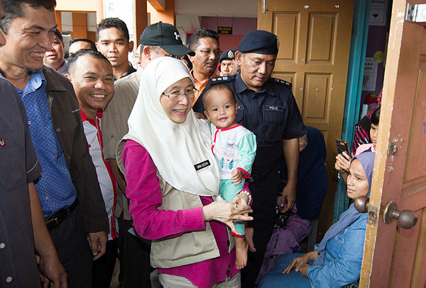 Deputy Prime Minister Datuk Seri Wan Azizah holds a baby which is housed in a temporary relief centre at SK Gual Tinggi, Rantau Panjang today — Bernama