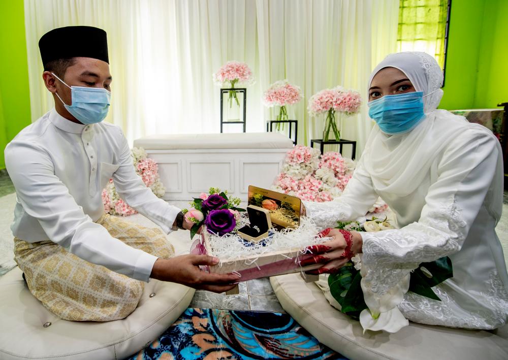 Abdul Khalib Abdullah (L) and his bride Nurul Fatihah Mat Husin, pose for a photo after their solemnisation ceremony, on April 4, 2020. — Bernama