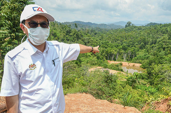 Deputy Minister of Water, Land and Natural Resources Tengku Zulpuri Shah Raja Puri points to the reservoir water from an iron ore mine near a Orang Asli settlement, while visiting the Batek Orang Asli community in Kampung Kuala Koh. — Bernama
