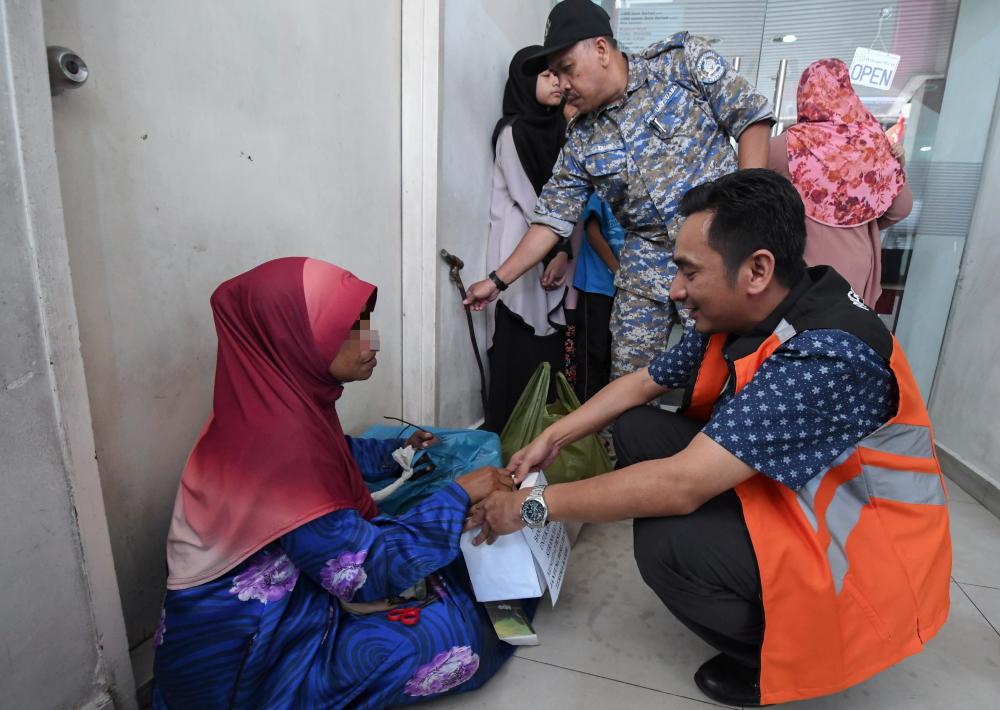 Welfare Department staff examine a begging container that was seized after detaining a Thai beggar during an operation to round up beggars in Kota Baru on May 26, 2019. — Bernama