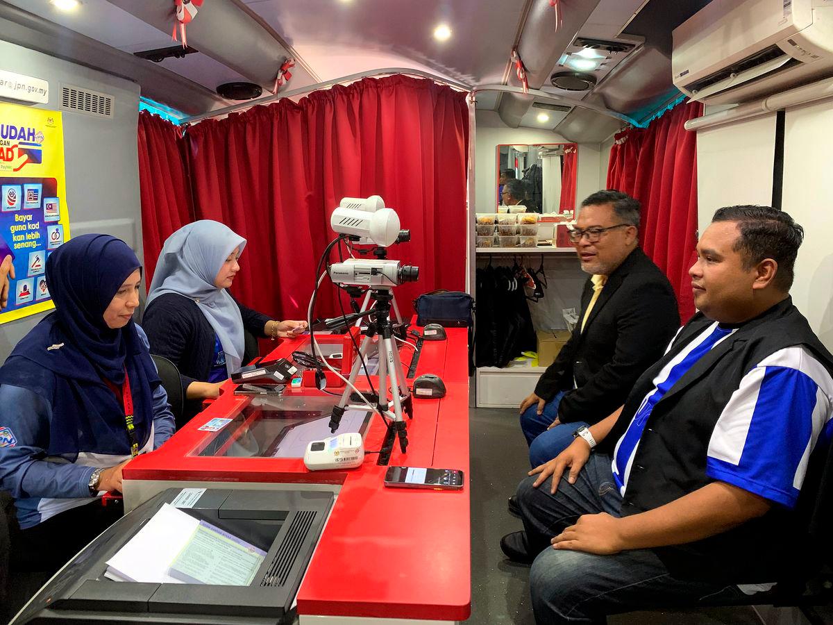 Seorang pengunjung, Mohd Shahir Khassin, 38 (kanan) mengambil peluang memperbaharui kad pengenalan di Bas Mekar Jabatan Pendaftaran Negara (JPN) pada Program MADANI Rakyat (PMR) 2025 Kelantan di perkarangan Stadium Sultan Muhammad IV , semalam - BERNAMA
