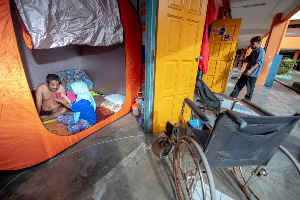 Flood victim, Norizah Mat Yusof, 45, feeding her husband, Zulkifli Ya, 62, who has stroke in an evacuation centre in Sekolah Kebangsaan Gual Tinggi Rantau Panjang on Dec 5, 2019. — Bernama