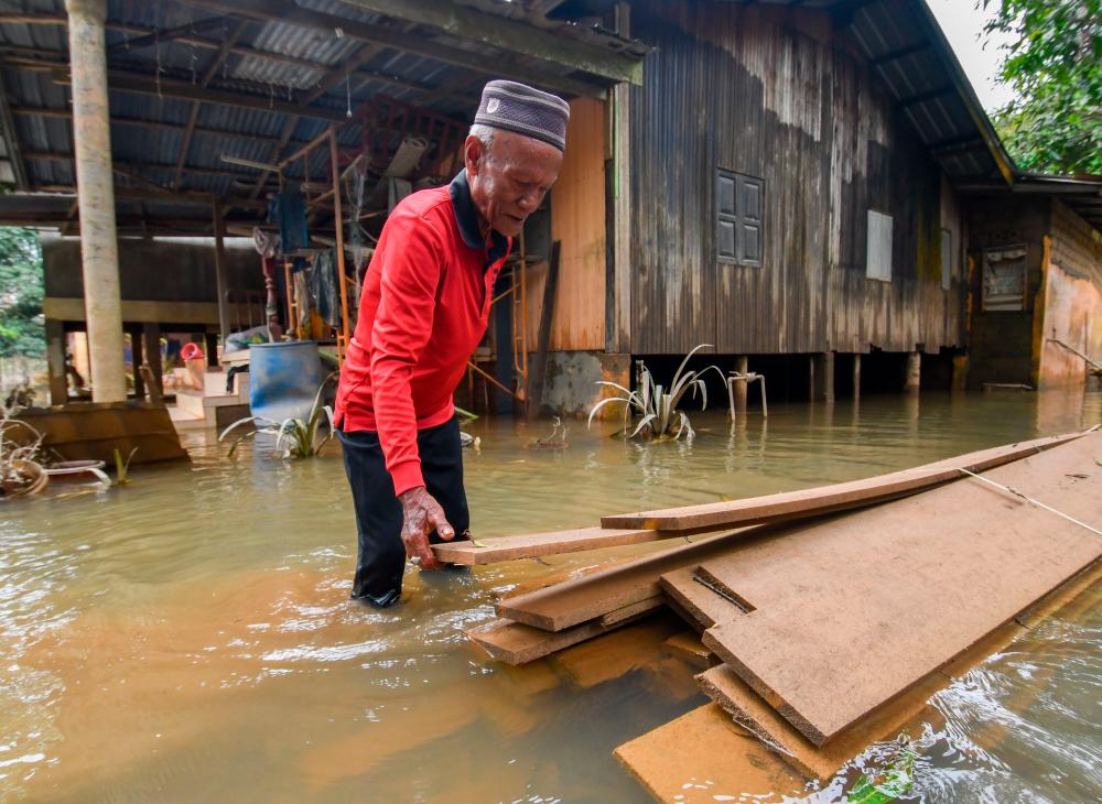 PASIR MAS, Dec 26 -- Villager, Che Ali Che Mud, 60, inspects the boards that will be used to repair his house that also sank following the recent flood incident during a survey of Kampung Tersang, Rantau Panjang today. BERNAMAPIX