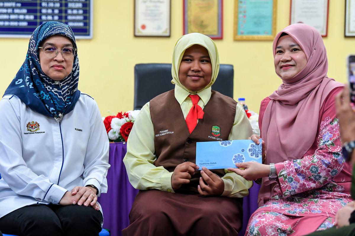 Education Minister Fadhlina Sidek presents a contribution to 12-year-old Putri Qisya Nur Izzat, who lost her entire family in last week’s Sungai Korok tragedy, during a visit to offer support - Photo by BERNAMA
