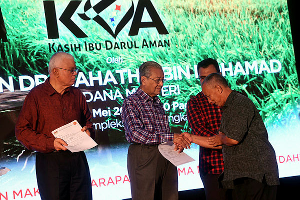 Prime Minister Tun Dr Mahathir Mohamad hands over donations to farmers during a ceremony at the Langkawi District Civil Defence Complex. - Bernama
