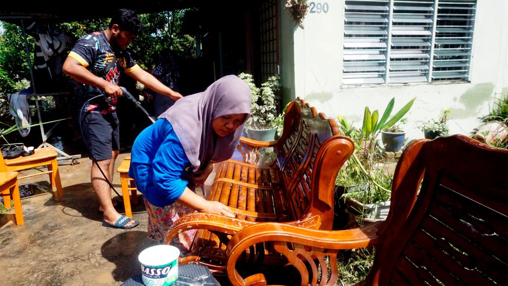 Penduduk membersihkan perabot yang diselaputi lumpur dalam kejadian banjir susulan air pasang besar di Kampung Bukit Belah/BERNAMAPix