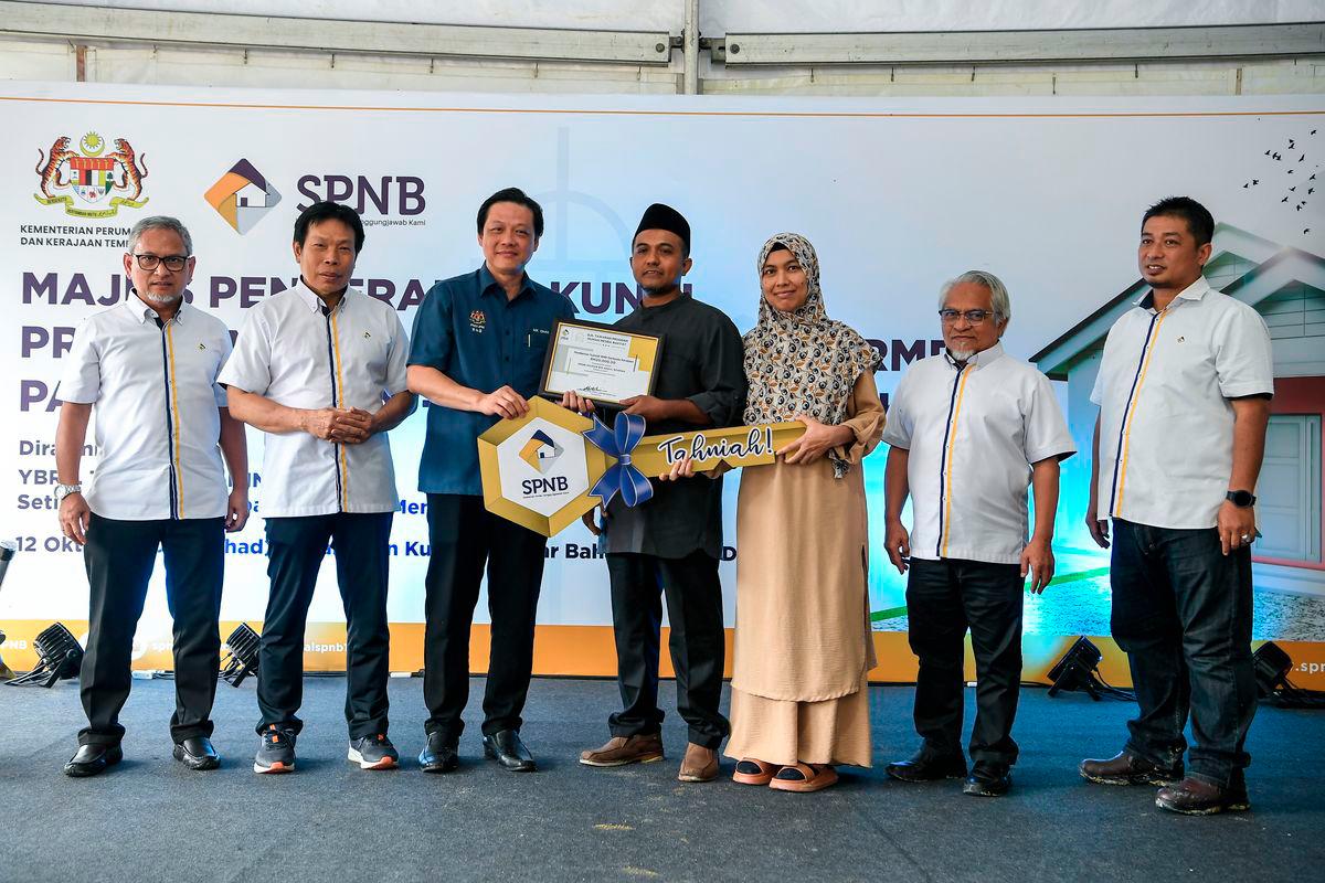 The Political Secretary to the Prime Minister, Chan Ming Kai, handed over a mock key to some recipients of the Rumah Mesra Rakyat (People’s Friendly Homes) at the Key Handover Ceremony for Rumah Mesra Rakyat in Kedah state, held at Kampung Badlishah today. Also present was the Chairman of Syarikat Perumahan Negara Berhad (SPNB), Datuk Prof Dr Mohd Azmi Mohd Lila (second from left). - BERNAMA