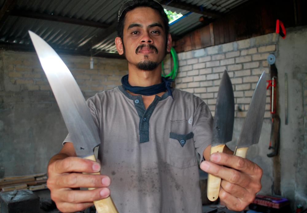 Mohd Zairy Yusop, 37, from Kampung Permatang Tok Dik holds up the knives he made in his workshop in Kulim, on March 27, 2019. — Bernama