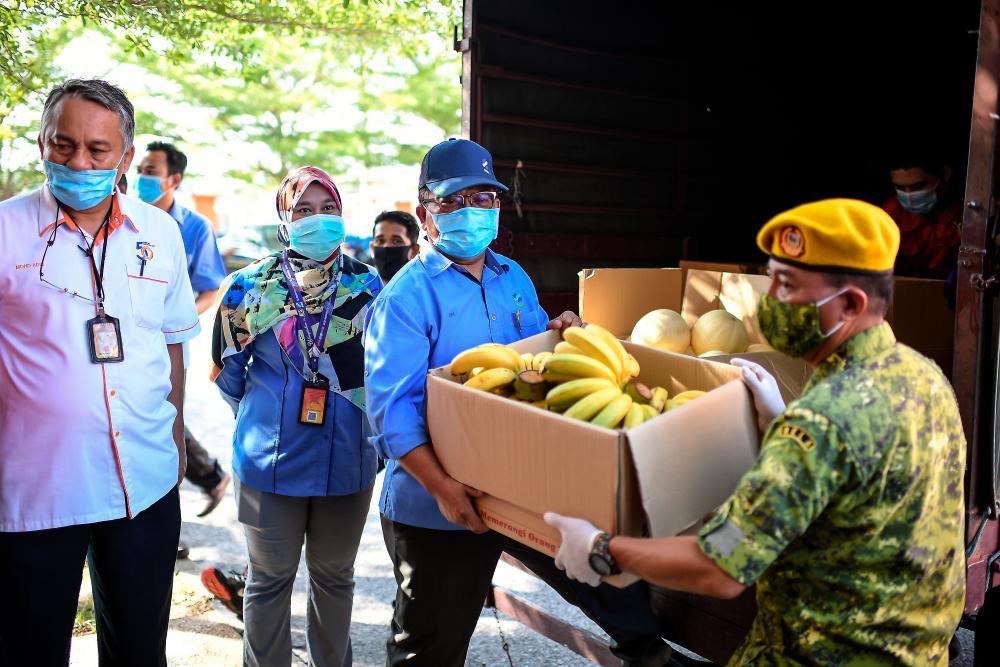 Kedah Federal Agricultural Marketing Authority (Fama) director Isa Hamzah (3L) presents fresh fruit donations to members of the Civil Defense Force (APM) and the Malaysian Volunteer Department (RELA) in charge of the Movement Control Order (MCO) at the Kedah State Civil Defense office in Alor Star today. - Bernama