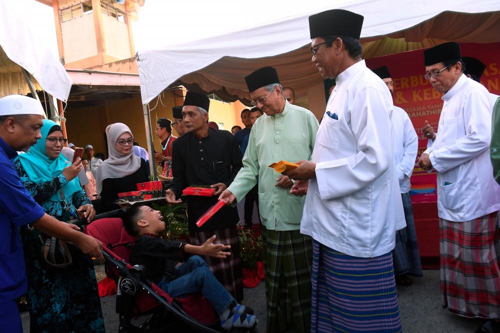 Prime Minister Tun Dr Mahathir Mohamad hands over donations to special needs children at a breaking-of-fast and welfare event at Masjid Nurus Salam, Kampung Ewa in Langkawi tonight. - Bernama