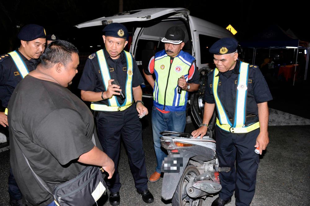 Ismasuhaimi Shariff (C) director of State Road Transport Department (JPJ) with his officers inspect a motorcycle during the Op Tahun Baharu Cina (TBC) road safety operation for the Chinese New Year festive period at the Darulaman Highway near Alor Star Hospital, on Feb 2, 2018. — Bernama