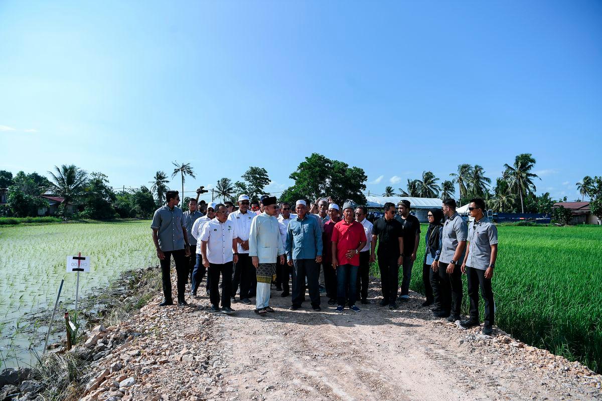 Perdana Menteri, Datuk Seri Anwar Ibrahim, berbincang sesuatu bersama sebahagian pesawah ketika mengadakan lawatan ke Projek Pembangunan Infrastruktur bagi menyokong Program Penanaman Padi Lima Musim di kawasan Muda dalam tempoh dua tahun, bertempat di Kampung Kemboja, Jerlun, hari ini.- fotoBERNAMA