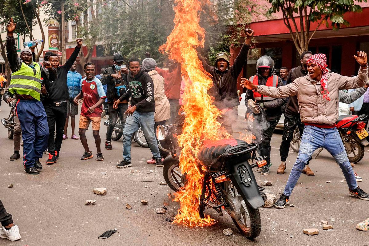 Demonstrators react near a burning motorbike during a protes in nairobi on June 17, 2025. (Photo by SIMON MAINA / AFP)