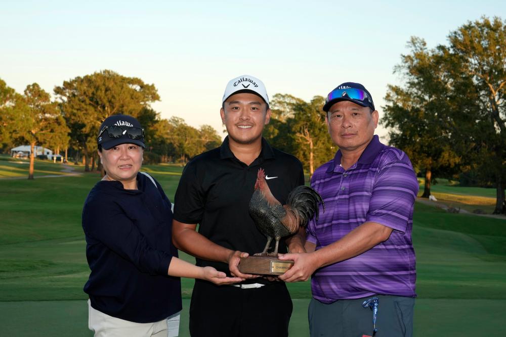 $!Yu (centre) poses with the trophy and his parents. – Getty Images/PGA TOUR