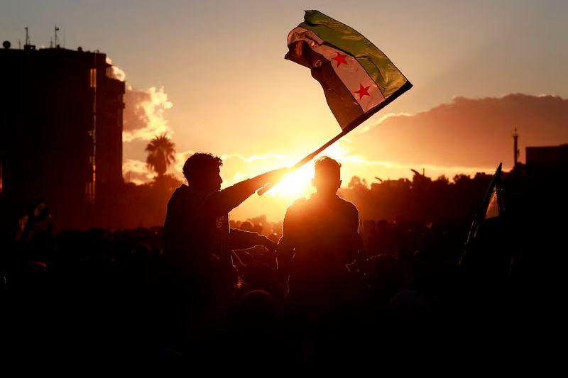 A person holds up the flag adopted by the new Syrian rulers in the Damascus old city - REUTERSpix