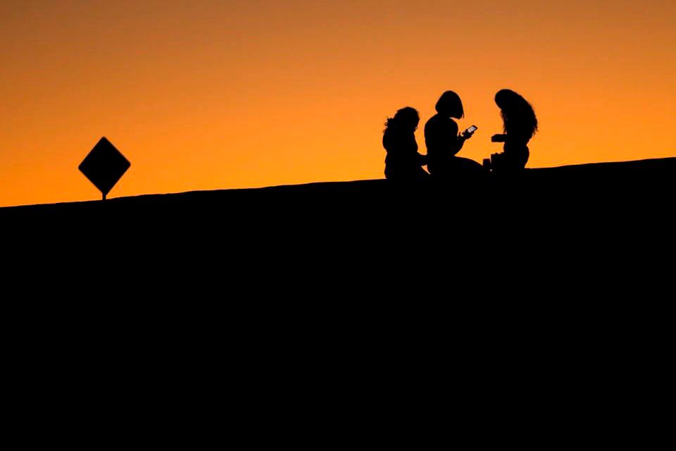 Young girls look at their phones as they sit on a hillside after sun set in El Paso, Texas, U.S., June 20, 2018. REUTERSpix