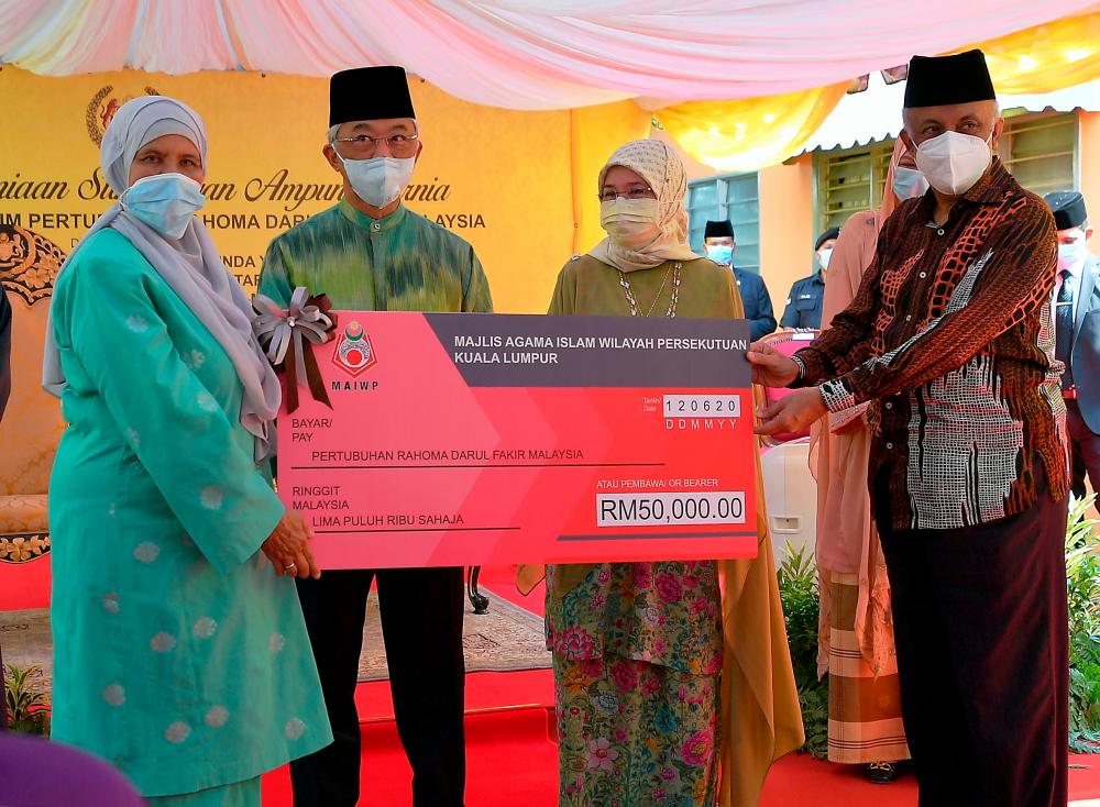 Yang di-Pertuan Agong, Al-Sultan Abdullah Ri’ayatuddin Al-Mustafa Billah Shah and Raja Permaisuri Agong, Tunku Hajah Azizah Aminah Maimunah Iskandariah present a RM50,000 donation from the Federal Territories Islamic Religious Council, represented by its chairman, Datuk Seri Syed Hussien Abd Kadir (R) to Pertubuhan Rahoma Darul Fakir Malaysia president Datuk Faridah Omar Shah (L) today. - Bernama