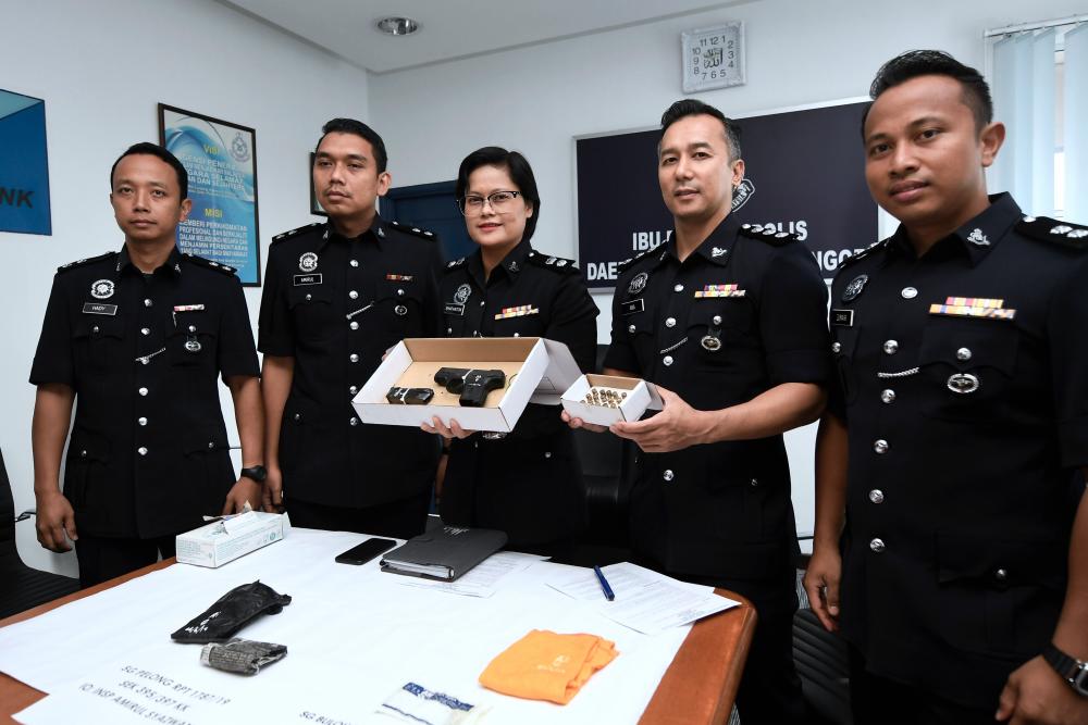 Sungai Buloh District Police Chief Supt Shafa’aton Abu Bakar (C) shows off a Ruger pistol with 16 bullets taken during the capture of ‘Black Ruger’ gang members, at the Sungai Buloh District Police Headquarters on June 28, 2019. - Bernama