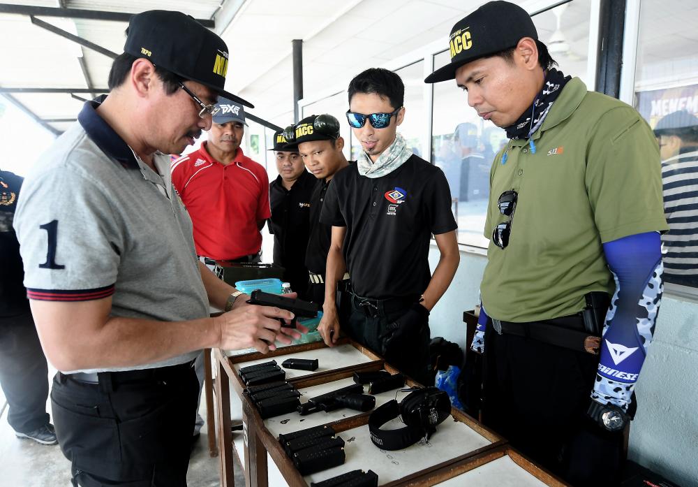 Malaysian Anti-Corruption Commission (MACC) deputy chief commissioner (Operation) Datuk Seri Azam Baki (L) is having a look at the shooting equipment during the Shooting Program with the Corporate Communications Unit (UKK) Enforcement Agency in the Field of Kajang Prison Coach, on April 20, 2019. — Bernama